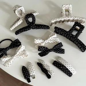 Close-up of black and white polka dot hair clips and bow scrunchie set on white background