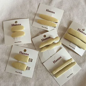 Detail of six yellow fabric-covered hair clips in various shapes on display card