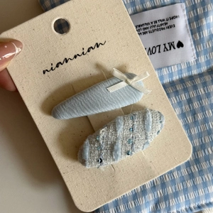 Detail of blue textured floral BB clips with a small white bow on display card