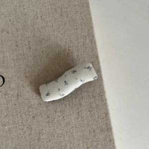 Gros plan d'une pince à cheveux florale avec de délicats motifs violets sur tissu blanc