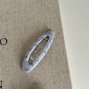 Vue détaillée d'une pince à cheveux en tissu fleuri violet clair sur une toile beige