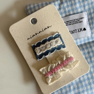Detail of blue denim lace clip and cream chiffon hairpins with sequins on card