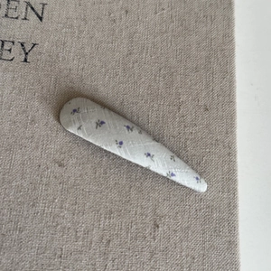 Gros plan détaillé d'une pince à cheveux en tissu fleuri bleu sur lin texturé