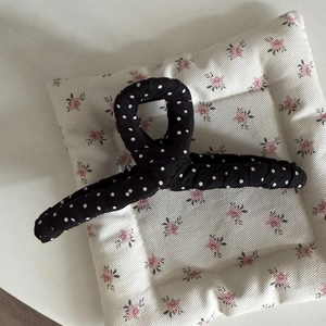 Close-up of black and white polka dot fabric hair claw clip with soft textile texture