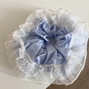 Macro detail of blue polka dot scrunchie featuring white lace and layered mesh frills