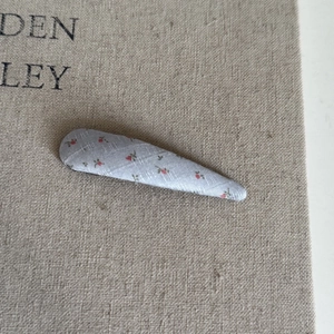 Détail rapproché d'une pince à cheveux en tissu bleu clair avec motifs floraux rouges