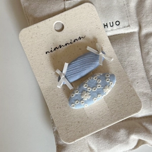 Detail of blue fabric hair clips with daisy embroidery and small white bows