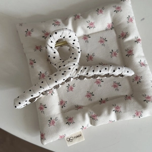 Close-up of large hair claw clip featuring white fabric with black polka dots and metal spring