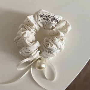 Detail of polka dot scrunchie with ribbon bow, pearl pendant and brand label tag