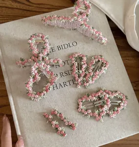 Detailed view of pink floral embroidery hair clips and grips set on a rustic background