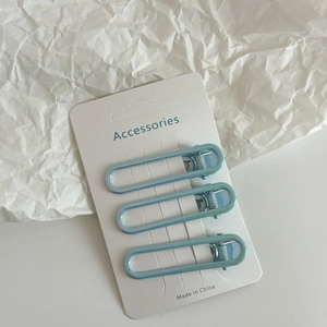Lot de trois barrettes à cheveux ovales en métal bleu clair sur une carte blanche épurée