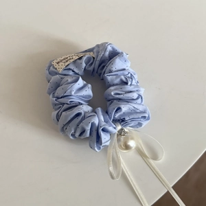 Detail of blue polka dot scrunchie with white ribbon bow and large pearl pendant