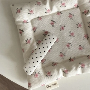 Detail of quilted floral pet mat with black polka dot pillow and a branded woven label
