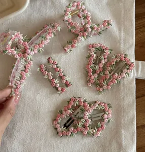 Close-up of pink floral embroidery and needlework detail on fabric hair clips