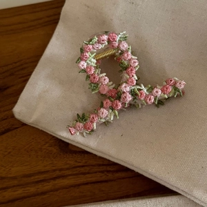 Pink sunset floral embroidery hair claw clip on beige canvas and wooden background