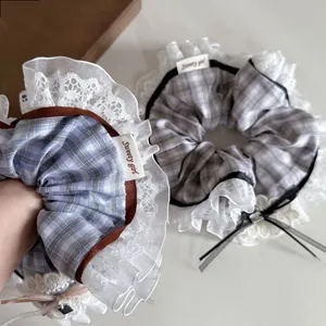 Macro detail of plaid cotton hair scrunchies with tiered lace trim and sweet ribbon ties