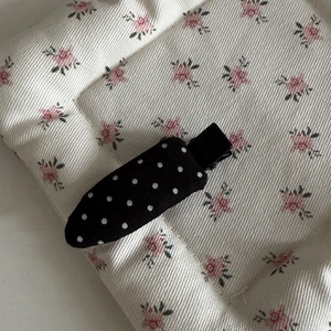 Detailed close-up of a French style black and white polka dot fabric duckbill hair clip
