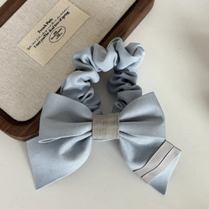 Detail of light blue bow scrunchie with grey fabric knot and decorative ribbon stripes