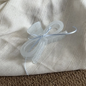 Detail view of large white hair claw clip with light purple ribbon on fabric