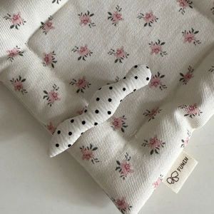 Detailed view of polka dot bow hair clip on soft ribbed fabric with floral pattern