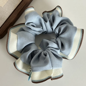 Blue and cream satin scrunchie with striped edges and a small silver metal charm