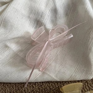 Detail of pink acrylic bow hair claw with silk ribbon on a textured background