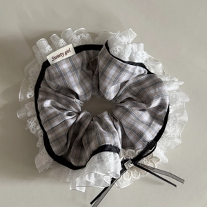 Detail of grey plaid hair scrunchie with white lace edges and a black ribbon bow