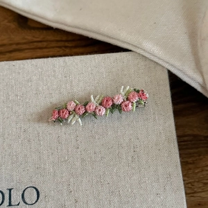 Close-up of handmade pink floral embroidery hair clip with intricate stitch patterns