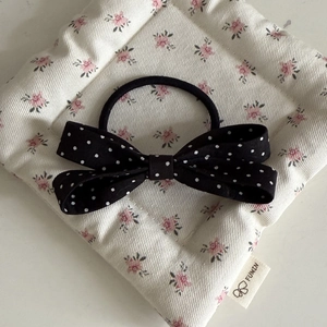 Close-up of black and white polka dot double bow hair tie on a floral fabric background