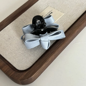Detail of light blue fabric bow hair claw clip on a minimalist wooden display tray