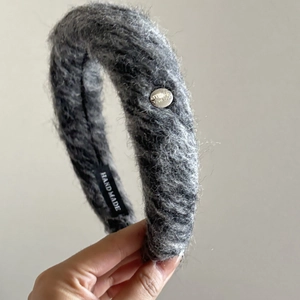 Detailed macro shot of gray plush knitted headband with handmade label and metal button