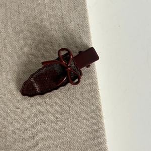 Detail shot of vintage burgundy bow hair clip with red and white plaid pattern texture