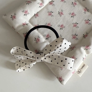 Detail of French style polka dot bow hair tie on a soft floral quilted background