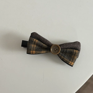 Close-up of vintage brown plaid bow hair clip with decorative button and metal beak clip