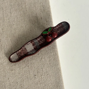 Detail of red plaid hair clip with decorative 3D cherries and green leaves