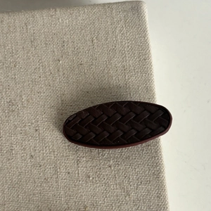 Barrette à cheveux vintage ovale en cuir tressé bordeaux sur surface en lin