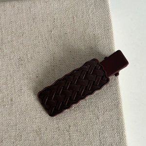 Pince à cheveux tressée vintage bordeaux avec bords ondulés sur fond en lin