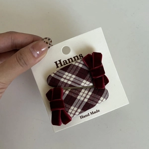 Detail of red plaid fabric hair clips with velvet bows on a handmade display card