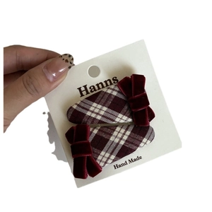 Pair of wine red plaid hair clips with velvet bows on a display card for women