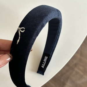 Macro detail of navy blue velvet headband with white bow embroidery and brand label