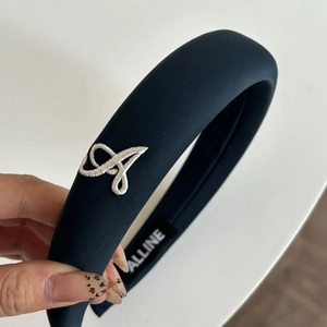 Detailed close-up of navy blue padded headband with white letter A embroidery and soft texture