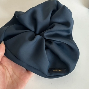 Detail view of large Prussian blue scrunchie with brand tag and pleated fabric texture