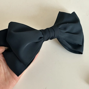 Close-up of a large black bow hair clip with detailed stitching and soft matte fabric