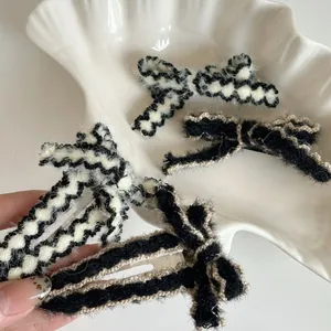 Detail of plush knit bow hair clip with silver duckbill metal clasp on ceramic tray