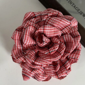 Detailed macro shot of vintage camellia hair claw with red houndstooth fabric texture