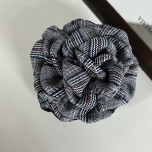 Close-up of a British plaid fabric rose clip with detailed woven petals in vintage colors