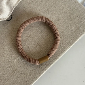 Élastique à cheveux marron à tissage spirale avec boucle lisse sur tissu neutre