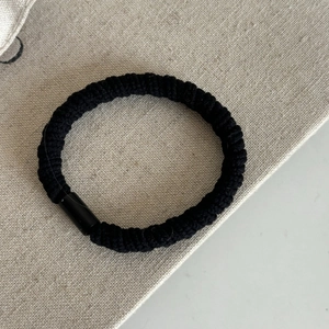 Gros plan d'un élastique à cheveux noir avec texture en spirale et joint cylindrique