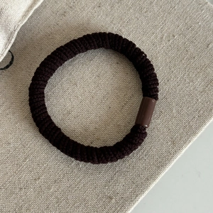 Vue détaillée d'un élastique à cheveux marron foncé avec texture tissée durable