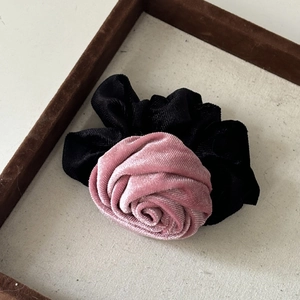 Detail of velvet scrunchie with a 3D pink rose decoration on a white jewelry tray
